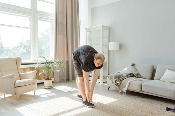 A person stretching calmly in a bright, minimalist room.